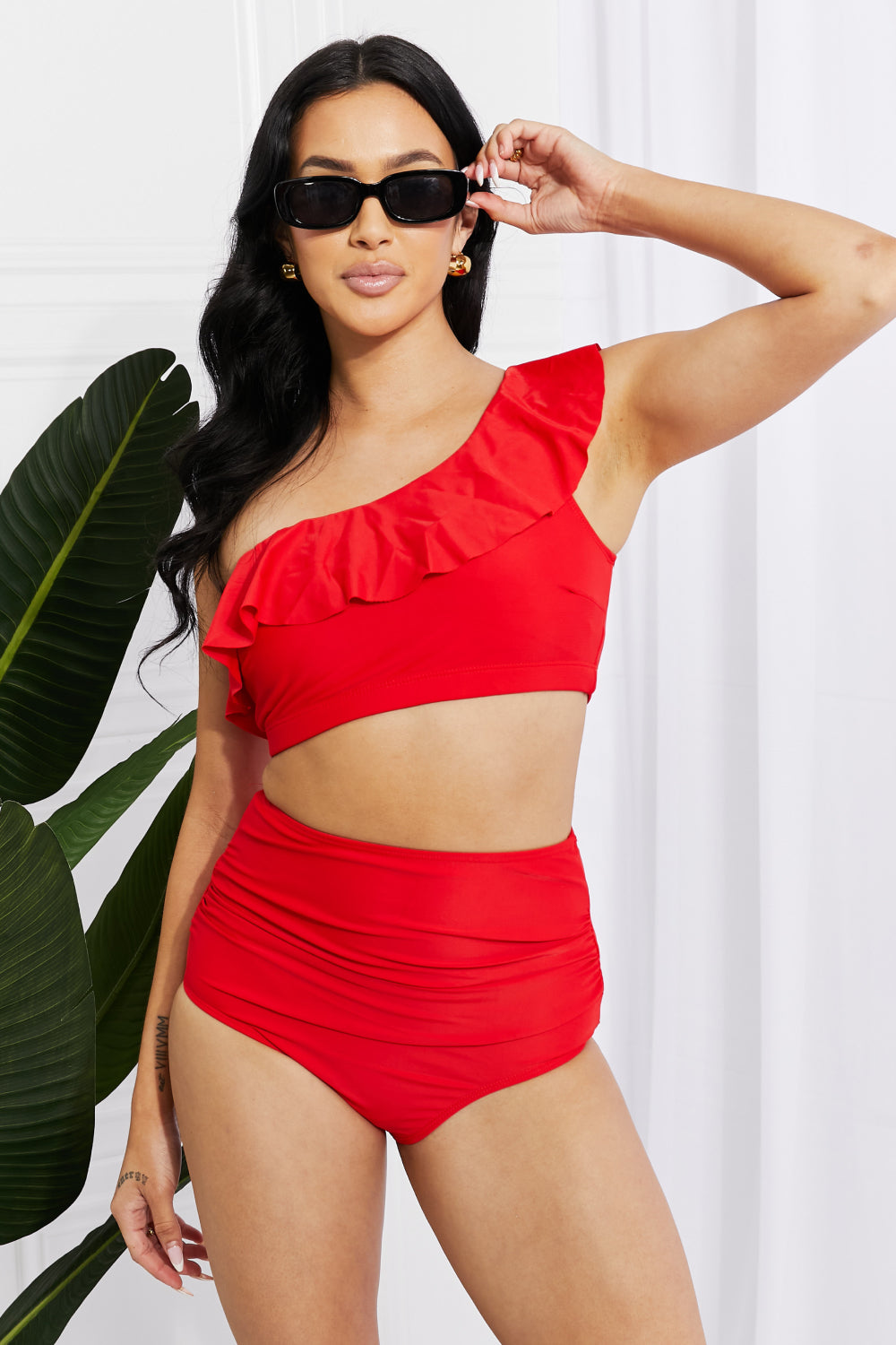 Discover elegance with the Marina West Swim Seaside Romance Ruffle One-Shoulder Bikini in Red. Perfect for the beach or pool, this two-piece set features a stylish asymmetrical top and high-waisted ruched bottoms. Enjoy comfort with removable pads and a blend of 83% polyester and 17% spandex. Ideal for confident swims and lounging in style.