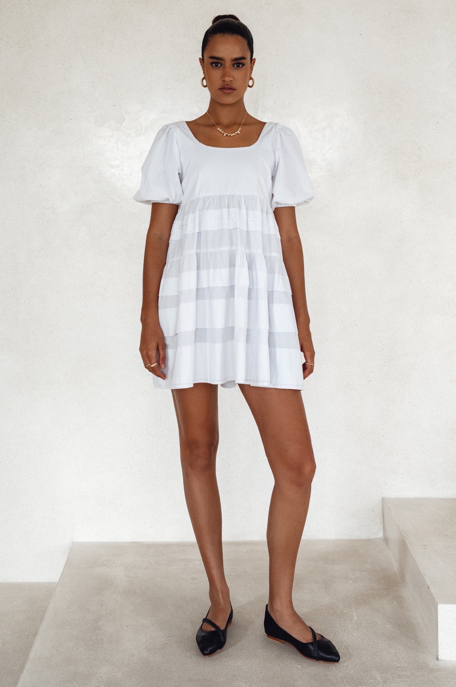 Achieve effortless femininity with the Andrea Babydoll Cotton Mini Dress. Handmade from breathable poplin cotton, this dress features elasticated sleeves, chic folds on the hem, and a flattering round neckline. 