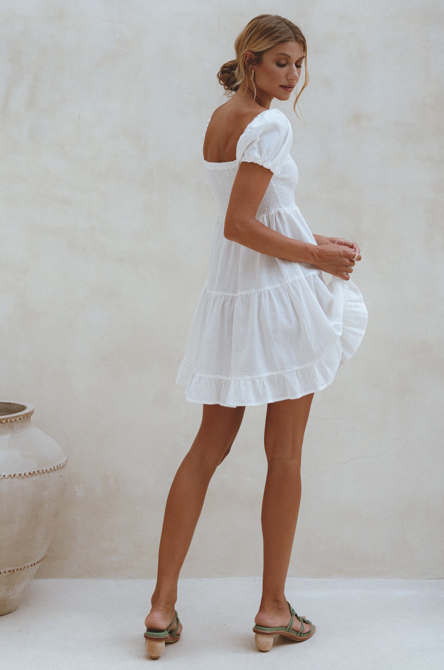 Experience effortless style with our Catalina Smocked Linen Mini Dress. Handcrafted from breathable crinkle linen, this dress features a smocked bodice, ruffles, and petite shell buttons for added elegance. Perfect for a beachside weekend with sandals or a chic lunch outing with strappy heels. 