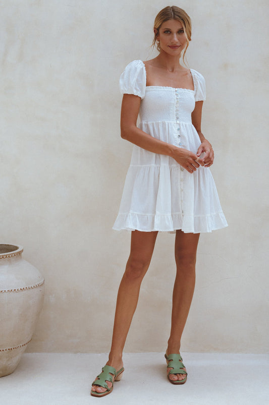 Experience effortless style with our Catalina Smocked Linen Mini Dress. Handcrafted from breathable crinkle linen, this dress features a smocked bodice, ruffles, and petite shell buttons for added elegance. Perfect for a beachside weekend with sandals or a chic lunch outing with strappy heels. 