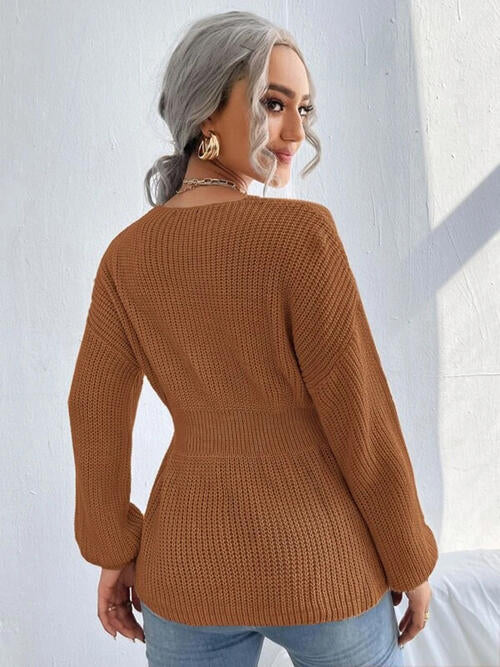 Woman wearing a chic notched dropped shoulder knit top in 100% acrylic. Available in sizes S to XL, offering a slightly stretchy and comfortable fit. Easy care with machine wash cold and tumble dry low. 