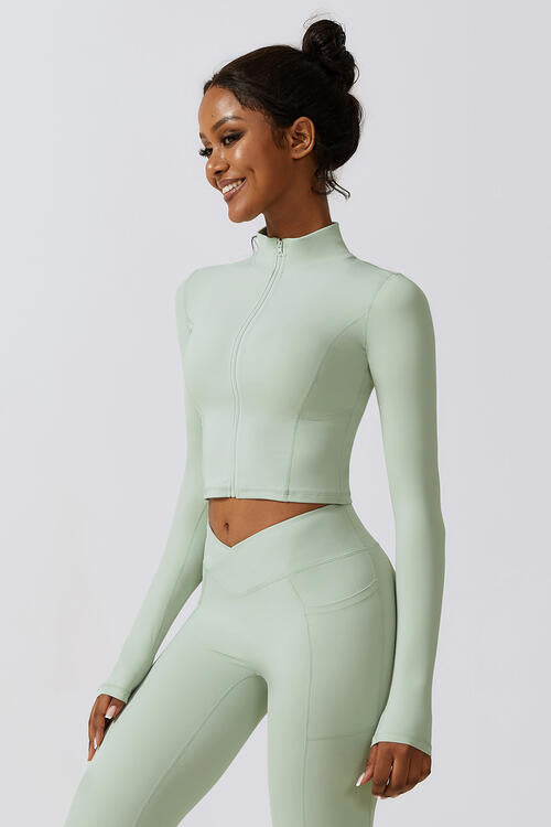 Woman wearing a zip-up long sleeve cropped active top in a highly stretchy blend of 78% nylon and 22% elastane. Available in sizes S to XL, offering a comfortable fit. Easy care with machine wash cold and tumble dry low.