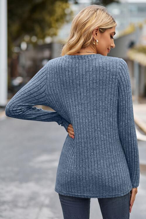 Woman wearing a chic ribbed half button long sleeve knit top in a blend of 60% polyester, 35% rayon, and 5% spandex. Available in sizes S to 2XL, offering slight stretch for comfort