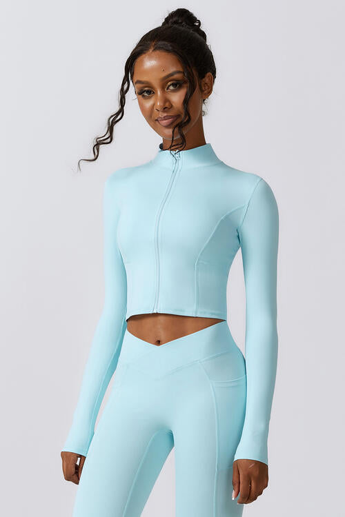 Woman wearing a zip-up long sleeve cropped active top in a highly stretchy blend of 78% nylon and 22% elastane. Available in sizes S to XL, offering a comfortable fit. Easy care with machine wash cold and tumble dry low.