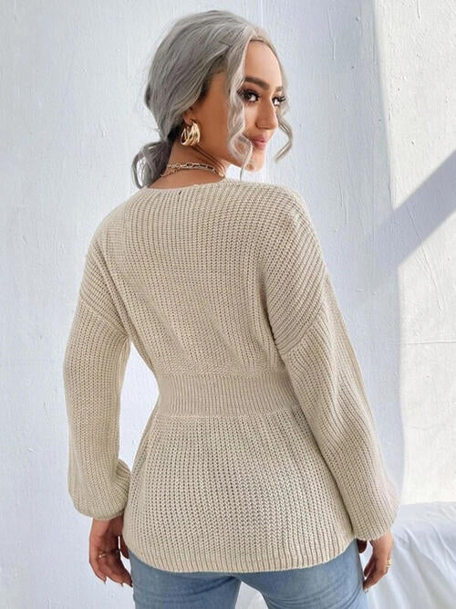 Woman wearing a chic notched dropped shoulder knit top in 100% acrylic. Available in sizes S to XL, offering a slightly stretchy and comfortable fit. Easy care with machine wash cold and tumble dry low. 