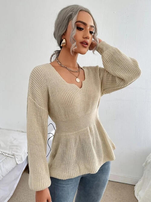 Woman wearing a chic notched dropped shoulder knit top in 100% acrylic. Available in sizes S to XL, offering a slightly stretchy and comfortable fit. Easy care with machine wash cold and tumble dry low. 