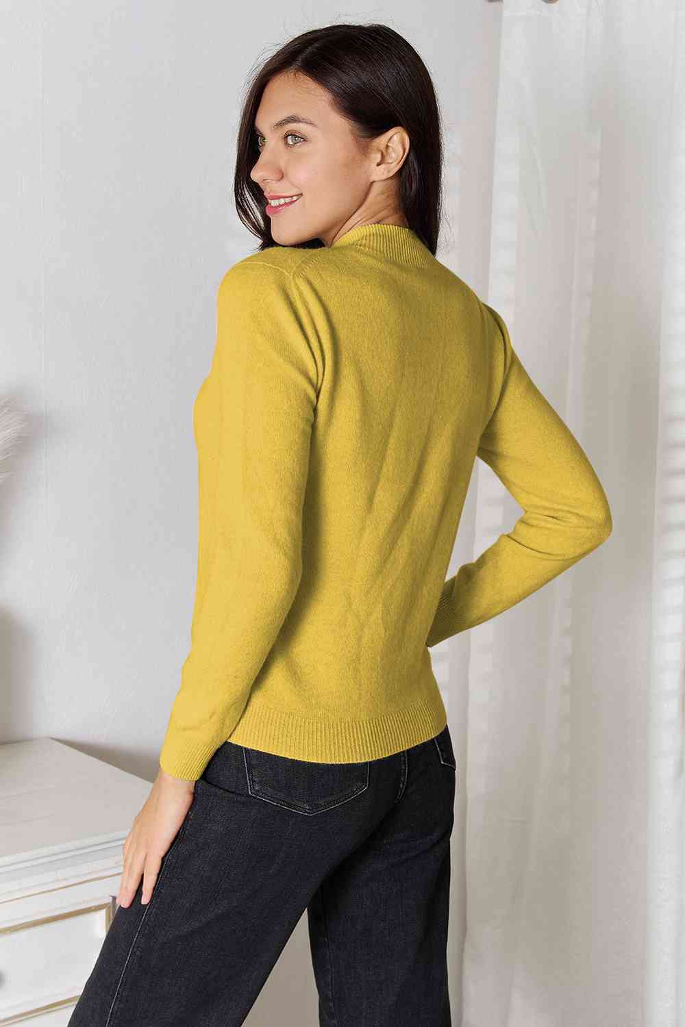 Woman wearing a classic mock neck long sleeve knit top in 100% wool, perfect for winter. Available in sizes S to 2XL.