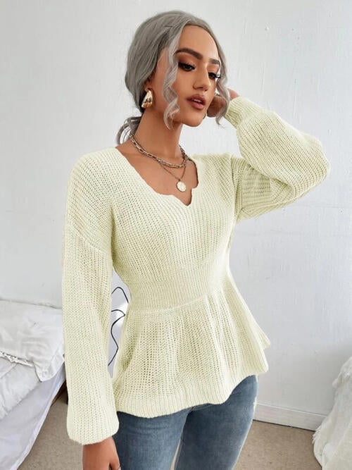 Woman wearing a chic notched dropped shoulder knit top in 100% acrylic. Available in sizes S to XL, offering a slightly stretchy and comfortable fit. Easy care with machine wash cold and tumble dry low. 