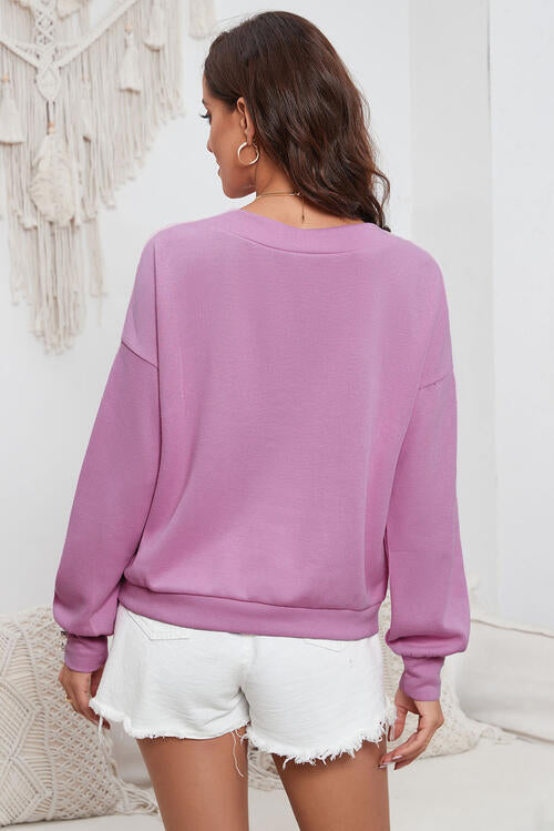 Woman wearing a classic V-neck buttoned long sleeve knit top in a blend of 50% polyester and 50% rayon. Available in sizes S to 2XL, offering a slightly stretchy and comfortable fit. 