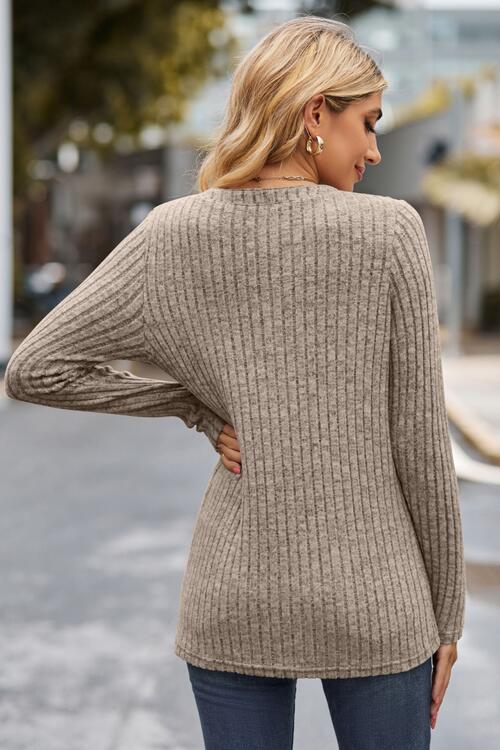 Woman wearing a chic ribbed half button long sleeve knit top in a blend of 60% polyester, 35% rayon, and 5% spandex. Available in sizes S to 2XL, offering slight stretch for comfort