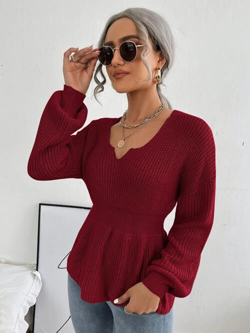 Woman wearing a chic notched dropped shoulder knit top in 100% acrylic. Available in sizes S to XL, offering a slightly stretchy and comfortable fit. Easy care with machine wash cold and tumble dry low. 