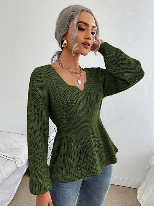 Woman wearing a chic notched dropped shoulder knit top in 100% acrylic. Available in sizes S to XL, offering a slightly stretchy and comfortable fit. Easy care with machine wash cold and tumble dry low. 